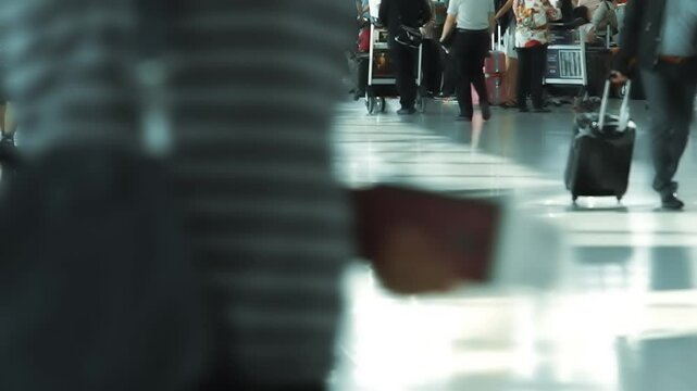 Selective focus on travelers at a busy airport waiting to check in and board. Passengers handle luggage, check flight info, and prepare travel documents amid the bustling scene