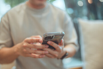 Close up man wears casual clothes hold use mobile cell phone sits alone at table in coffee shop cafe restaurant, rest relax