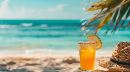 A drink and straw hat on the beach.