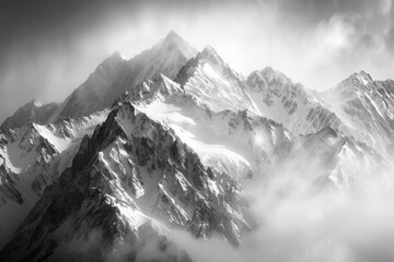 Obraz premium Stunning black and white photograph of majestic snow-capped mountain peaks shrouded in mist and clouds, capturing the serene beauty of nature.