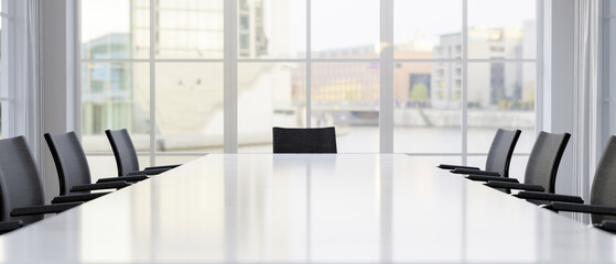A front view of a large white meeting table with black chairs in a contemporary white meeting room.