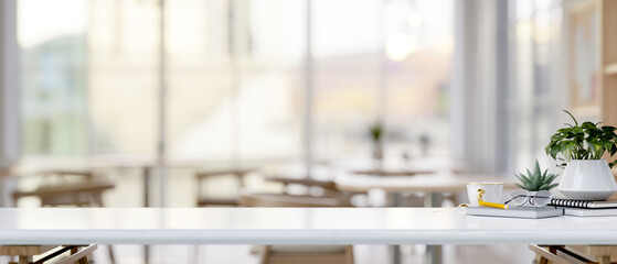 A white tabletop with a copy space and decorative stuff in a comfortable coffee shop or restaurant.