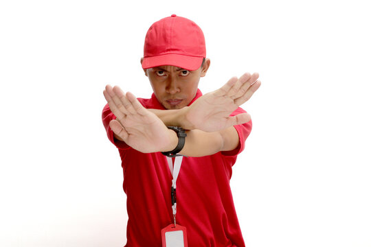 Asian delivery man or courier crosses his arms in a stop or refuse gesture, isolated on white background. Concepts of limitations, restrictions, refusal of service, and boundaries in delivery services