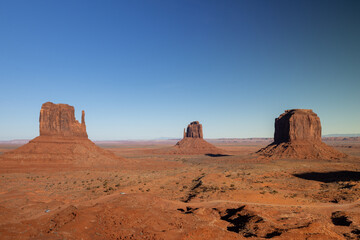 Fototapeta premium The Monument Valley Navajo Tribal Park in Arizona offers a breathtaking panoramic view of iconic red rock formations under a clear blue sky, perfect for outdoor adventures and sightseeing