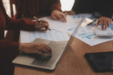 Group of confident business people point to graphs and charts to analyze market data, balance sheet, account, net profit to plan new sales strategies to increase production capacity.