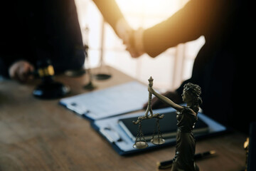 Lawyer shaking hands with a client making about documents, contracts, agreements, cooperation agreements with a female client at the lawyer's desk and a hammer at the table.