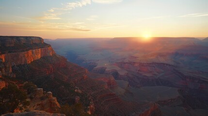 The dramatic and breathtaking sight of a sunset over a canyon, with the rock formations glowing in the last light of day, highlights nature's grandeur.