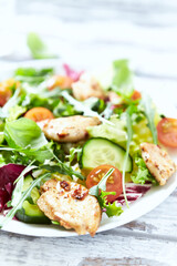 Salad with Chicken Breast, Cherry Tomatoes, Cucumber, Rocket and fresh Basil. Bright wooden background. Close up.