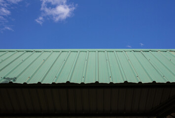 Green metal sheet roof, blue sky background.