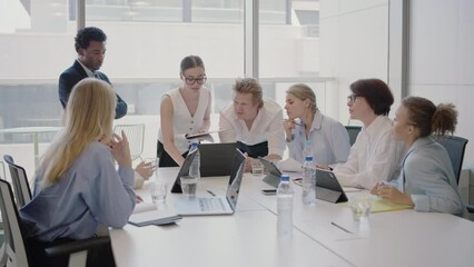 A diverse group of corporate employees collaborating and discussing projects during a business meeting in a modern office setting, emphasizing teamwork and professional interaction