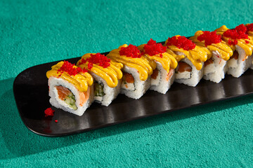 Close-Up of Salmon Rolls with Curry Sauce and Tobiko Caviar on a Black Plate