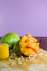 Fresh mango juice. A splash of mango cocktail on a black background. Ice cubes fall into the mango juice. © doublealpha