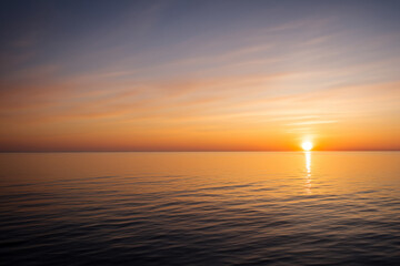 Obraz premium Sunset over the sea with horizon. Ocean landscape beach concept. Sun at sunset in the sky and sea. Sun at sunset on the horizon with sea and clouds lifestyle.