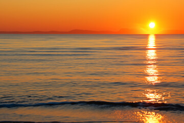 Obraz premium Sunset over the sea with horizon. Ocean landscape beach concept. Sun at sunset in the sky and sea. Sun at sunset on the horizon with sea and lifestyle clouds.