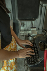 an asian woman hands typing on an old typing machine