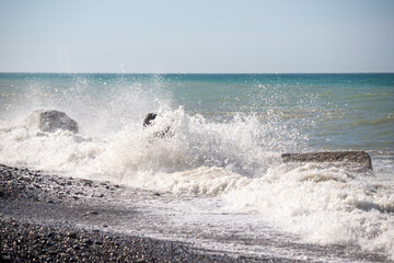 A sea wave breaks against the rocks, water splashes in the sky. Tidal wave.