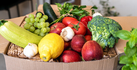 High angle view of farm grown fruits and vegetables in cardboard box. 