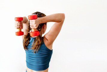 Rear view of female athlete doing triceps extension exercise with dumbbells, isolated on a white background, 