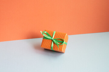 Orange gift box on gray desk. red wall background
