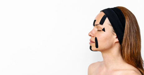 woman beauty model with head band applies facial contouring tape on white background 