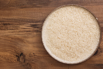 A bowl filled with rice placed on a wooden table, showcasing the simplicity and natural texture of the grain.