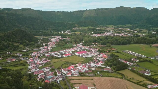 Miraduro do lombo dos milhos, furnas, azores, portugal with green hills and red-roofed houses, aerial view