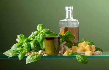 Pesto sauce and ingredients on a green background.