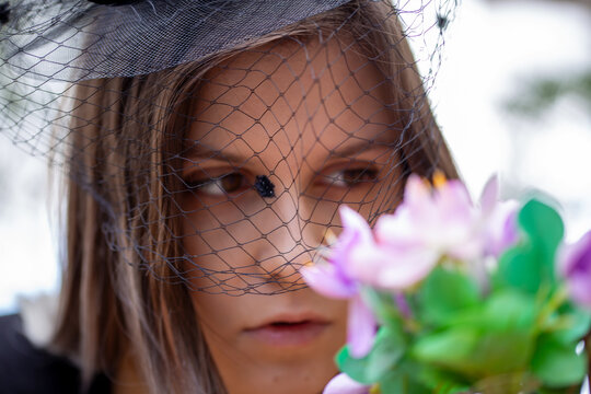 Nahaufnahme einer trauernden jungen Frau mit Trauerschleier  (Symbolbild, model released)