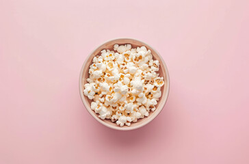 A close-up photo of a bowl filled with fluffy popcorn, against a pink background