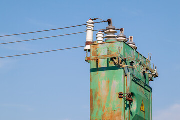 Old high voltage transformer with insulators and wires outdoors. Emergency power outages....