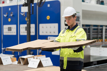 Male warehouse worker working and inspecting quality of cardboard in corrugated carton boxes warehouse storage