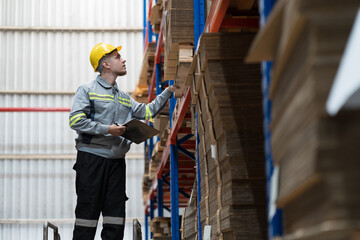 Fototapeta premium Male warehouse worker working and inspecting quality of material in warehouse storage. Male warehouse worker inspecting quality of barcodes on shelves pallet in warehouse