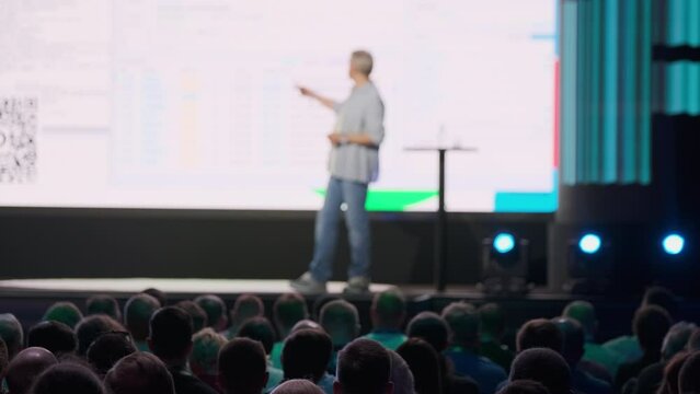 Professional speaker delivering a presentation on stage at a tech conference with a large engaged audience.