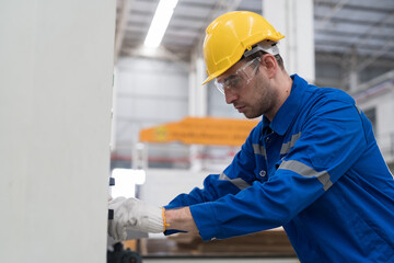 Male electrician engineer control electric system in industry factory. Factory male worker at work in the industry factory, work with CNC machine. Factory engineer male worker maintaining machine