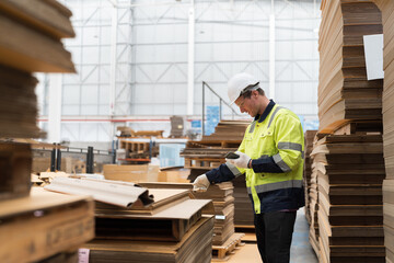 Fototapeta premium Male warehouse worker working and inspecting quality of cardboard in corrugated carton boxes warehouse storage