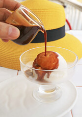 Hand pouring a shot of espresso on vanilla ice cream for a cup of Affogato