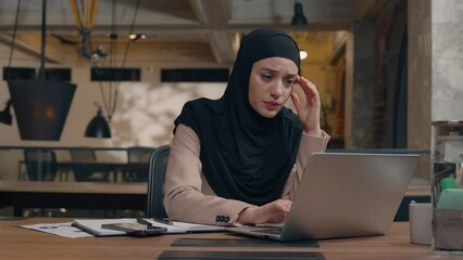 Displeased sad worker muslim islamic businesswoman in hijab upset online project mistake Arabian man businessman boss coach come help trainee solve problem excited happy woman working laptop in office