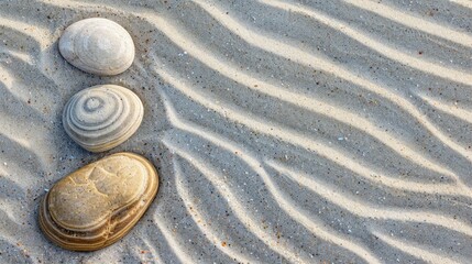 Smooth sea stones on textured sand with parallel wave lines