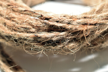 On a white background lies a skein of rope made from flax fibers.