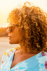 Side view portrait of cute middle age woman in outdoor leisure activity looking away. Warm sunset sunlight in background. People and summer holiday vacation. Travel destination female curly hair