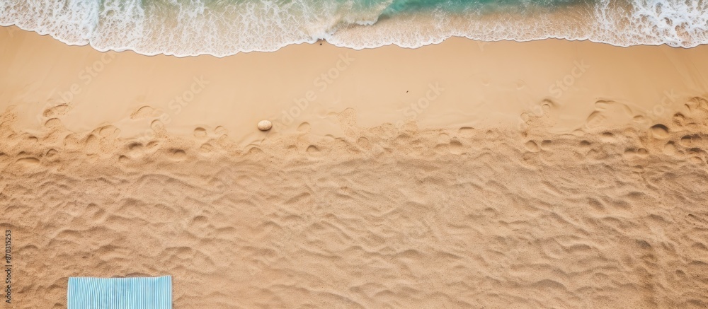 Aufkleber Sandy beach seen from above with towel border, summer accessories, and visible sand texture, creating a background with copy space image on the left side.