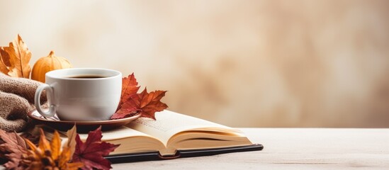 Autumn-themed decorations with a cup of delicious coffee, beside an empty book, set against a light background with copy space image.