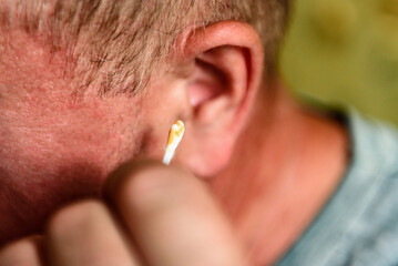 Man cleaning his ears with cotton swabs.
