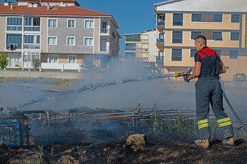 Fire in the field near the city. Firefighter extinguishes a fire.