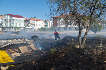 Fire in the field near the city. Firefighter extinguishes a fire.