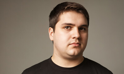 Fototapeta premium Portrait of a young man with short brown hair against a neutral background