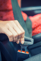 Woman fastens a seat belt in the car. Caucasian woman driver fastening car seat belt while sitting behind the wheel. close up hand.