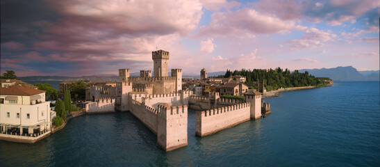 Panorama Aerial view of the morning Castello Scaligero di Sirmione, Lake Garda, Italy. Top view of Castello Scaligero di Sirmione with pink clouds in the background.