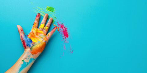 Left hand covered in colorful paint on blue background, left handers awareness day concept banner with copy space