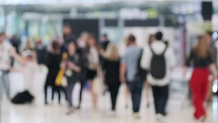 Blurred image of a busy crowd at a technology event or conference exhibition, showcasing attendees and networking opportunities.